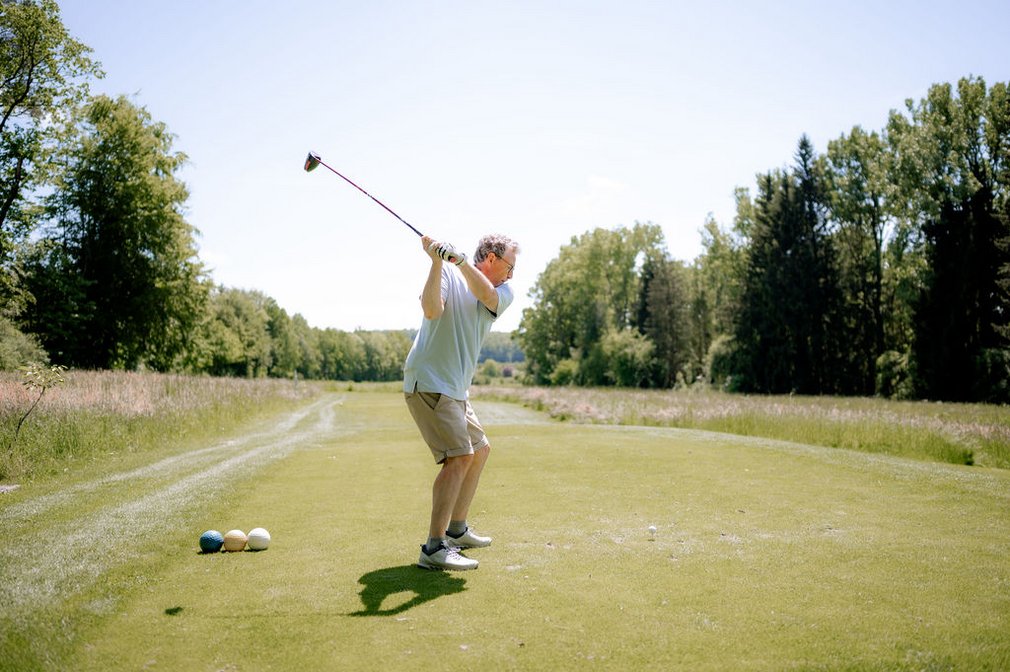 Ein Mann beim Abschlag eines Golfballs.