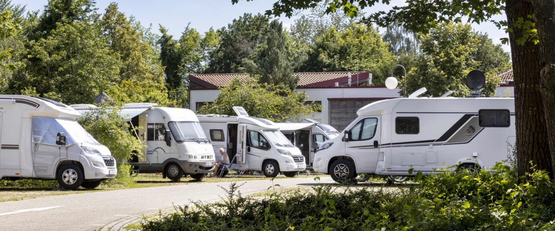 Ein Wohnmobilstellplatz mit mehreren Fahrzeugen.