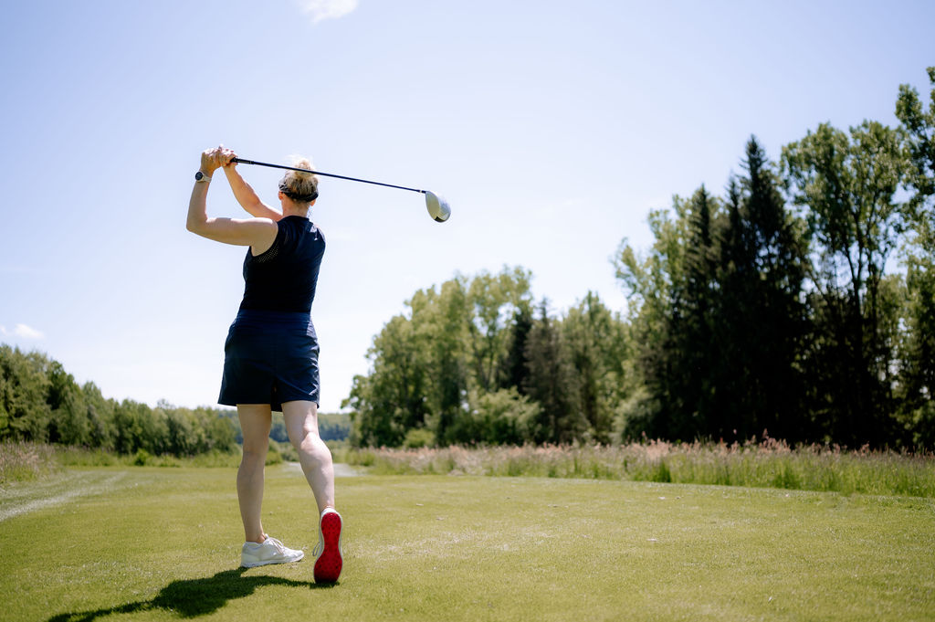 Eine Frau beim Abschlag eines Golfballs.